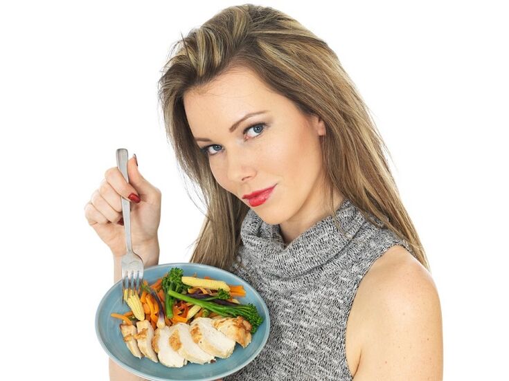 Chica comiendo pollo y verduras para bajar de peso